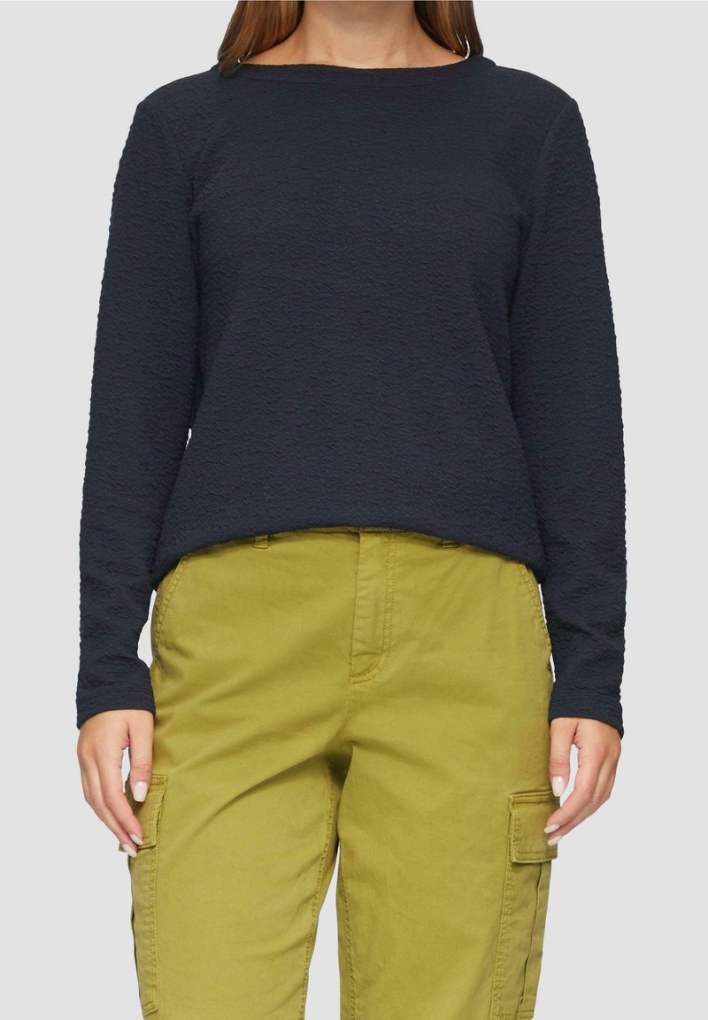 Top de manga larga texturizado en color navy con cuello redondo, combinado con pantalones cargo verde oliva que cuentan con bolsillos laterales y un ajuste recto.