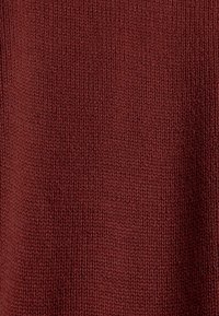 Tissu tricoté bordeaux avec une surface texturée, présentant un motif uniforme de fils entrelacés. Matériau doux de poids moyen.