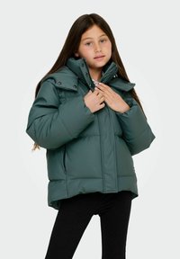 Grön vadderad vinterjacka med hög krage, tryckknappar och sidfickor, visad av en flicka med långt hår.