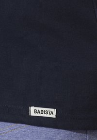Navy blue knitted shirt with ribbed texture and a white label reading "BABISTA" at the bottom hem.