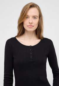 Schwarzes Langarmoberteil mit gerippter Textur, Rundhalsausschnitt und Knopfleiste mit fünf Knöpfen. Glatter Stoff, figurbetonte Form, keine sichtbaren Muster oder Akzente.