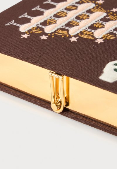 Gros plan d'une pochette en tissu marron avec des bords métalliques dorés et un fermoir doré, avec des motifs brodés de bougies et d'étoiles.