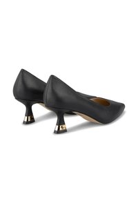 Una scarpa nera in pelle con punta appuntita e un piccolo tacco a zeppa decorato con una banda dorata. La superficie è liscia e lucida.