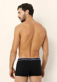 Boxeri scurți negri din bumbac, cu un design ajustat, având o talie moale etichetată 'yamamay' în violet, textură netedă și fără modele vizibile.
