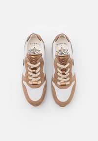 Sneakers in suede marrone e rete bianca con lacci beige, punta rotonda e design floreale sulla soletta. Presentano dettagli metallici.