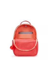 Mochila coral con diseño redondeado, material de tela, cierre de cremallera, bolsillo frontal y acento de pompones. Dispone de un compartimento acolchado para portátil.