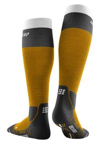 Kompressionssocken mit einem gerippten Muster, orange-gelber Körper und grau-weißen Akzenten. Robustes Design mit Logo und gemustertem Fußbett.