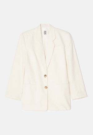 Cream-colored blazer made from textured fabric, featuring a single-breasted design, two front pockets, and gold-tone buttons.