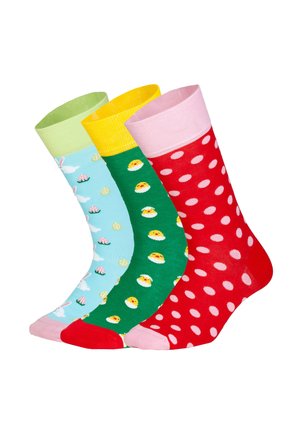 Tre farverige sokker med påskemotiver: blå med kaniner og æg, grøn med gule kyllinger og rød med lyserøde prikker.