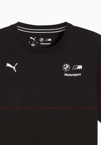 Sort t-shirt med rund hals, prydet med hvide Puma- og BMW-logoer samt en rød vandret stribe tværs over brystet. 100% bomuldsmateriale.