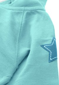 Turkusowa bluza z kapturem, ozdobiona naszywaną niebieską gwiazdą na rękawie, z prążkowanymi mankietami i gładką teksturą materiału.