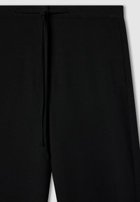 Czarne dresowe spodnie z elastycznym paskiem, gładką teksturą i bocznymi szwami. Charakteryzują się luźnym krojem i brakiem widocznych kieszeni.