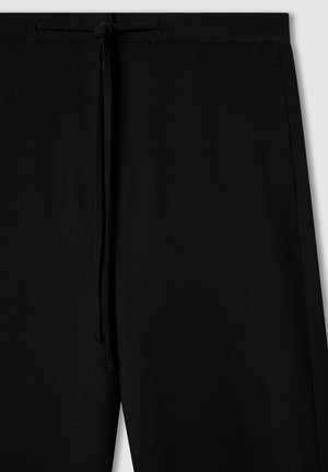 Czarne dresowe spodnie z elastycznym paskiem, gładką teksturą i bocznymi szwami. Charakteryzują się luźnym krojem i brakiem widocznych kieszeni.