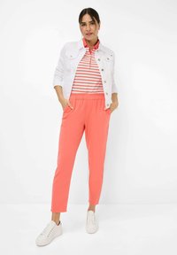Witte denimjas, rood-witte gestreepte polo, koraalkleurige broek met een elastische tailleband en witte sneakers.