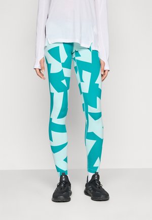 Leggins kuviollisessa teal- ja vaaleansinisessä värissä, joissa on geometrisia muotoja. Valmistettu joustavasta materiaalista, jossa on tiukka malli. Mustat urheilukengät.