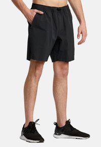 Black, lightweight swim shorts with an elastic waistband, side pockets, and a loose fit. Pairing with black athletic shoes.