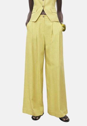 Yellow pinstriped wide-leg trousers with a high waist and side pockets, made of a textured fabric. Paired with a matching jacket.
