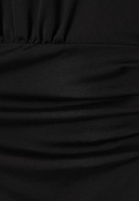 Tissu noir à texture lisse, présentant des plis froncés qui créent une dimension subtile et une coupe ajustée.