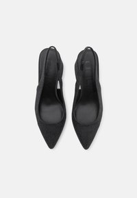 Escarpins noirs à bride arrière avec bouts pointus, dessus texturé orné de petits clous, et intérieur noir lisse. Design minimaliste, sans éléments métalliques visibles.