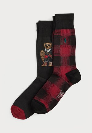 Dois pares de meias até à metade da panturrilha: um par preto com pontas vermelhas com um ursinho de pelúcia vestido de desporto, o outro em padrão xadrez preto e vermelho com um logótipo verde.