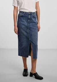 Denim midi-kjol i mörkblått med slits framtill, hög midja och traditionell femfickorsdesign. Bärs med svarta blockklackade mules.