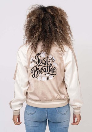 Giubbotto bomber in crema e beige, con ricami floreali e la scritta "Just Breathe" sul retro. Tessuto morbido con polsini a coste.