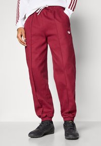 Bordo krāsas sporta bikses no kokvilnas ar elastīgām aprocēm, ar sānu šuvēm un baltu logotipu uz kreisā gurniem.