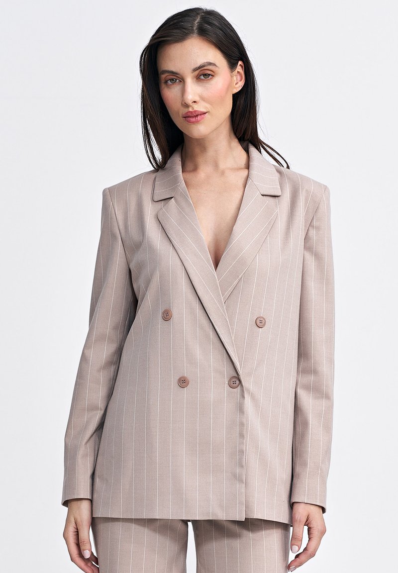 Jasno beżowa marynarka dwurzędowa z białymi pionowymi paskami, z klapami ze ścięciem i brązowymi guzikami, o luźnym kroju i gładkiej fakturze.
