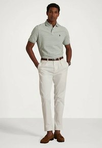 Randig polo skjorta i ljusgrön och vit, parat med krämfärgade byxor och bruna skor, med en avslappnad passform och klassisk krage.