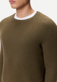 Olivgrön ribbstickad tröja med rund halsringning, långa ärmar och mjuk textur. Perfekt för vardagsbruk.