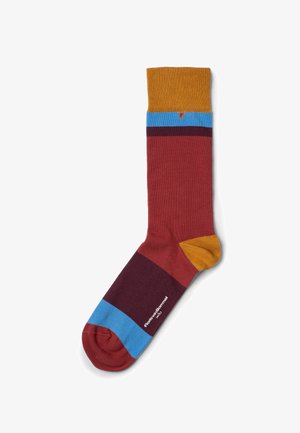 Chaussette colorée présentant un mélange de sections bordeaux, moutarde, bleu et violet. Tissu tricoté lisse avec bord-côte et talon contrastant.