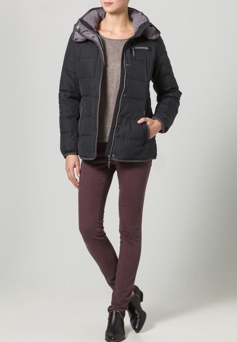 Svart puffjacka med grå huva, dragkedjeficka och tryckknappar, tillsammans med bourgogne-färgade strukturbyxor och svarta ankelstövlar.