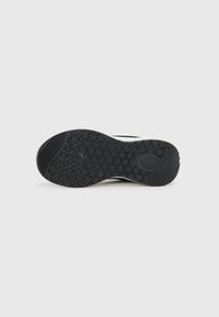 Black rubber shoe sole with textured circular patterns and ridges, featuring a smooth edge and a white accent near the heel.