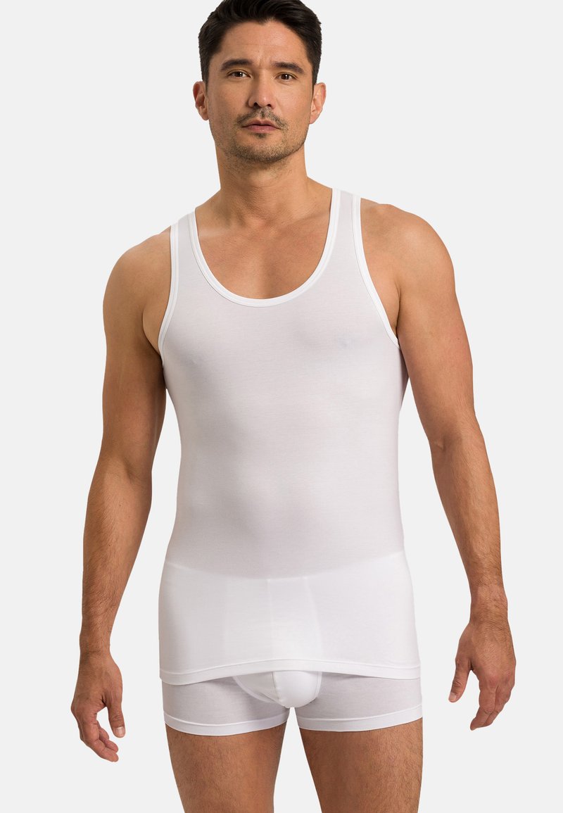 Bílý bavlněný top bez rukávů s širokými ramínky a přiléhavým střihem, spárovaný s bílými boxerky, vykazující hladkou texturu a minimální detaily.