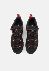 Sorte vandresko med overdel i ruskind og mesh, røde accenter og teksturerede gummisåler. Har multicolore snørebånd og træksløjfer.