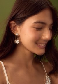 Srebrne naušnice sa dizajnom pahuljice, u visećem stilu s detaljnim ukrasima, viseće s male lance.