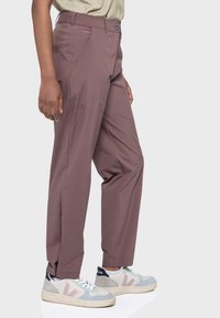 Schmal geschnittene, hochtaillierte Hose in einem sanften Mauve-Ton. Hergestellt aus einem leichten Stoff mit Taschen; kombiniert mit mehrfarbigen Sneakern.