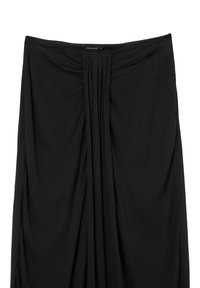 Jupe noire avec des plis froncés au centre avant, dotée d'une ceinture lisse et d'une petite étiquette en haut.