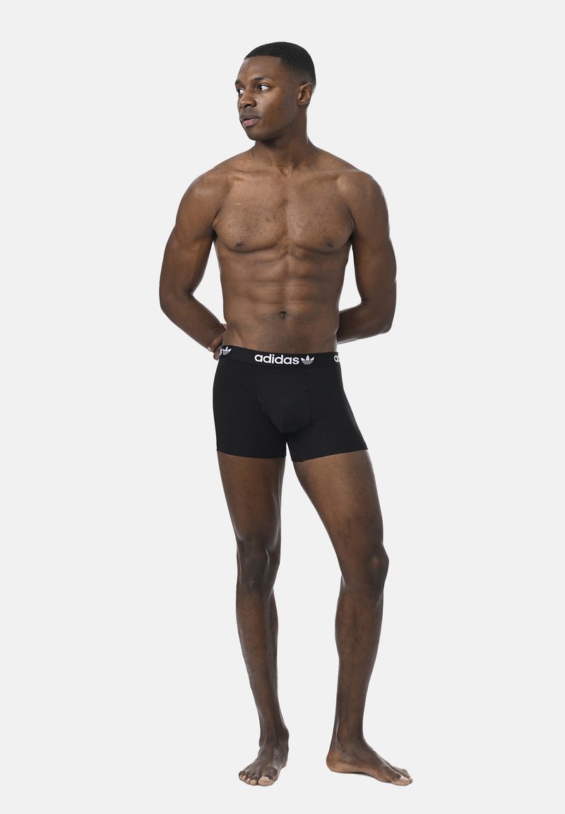 Schwarze Boxer Shorts mit engem Schnitt, mit einem weißen Adidas-Logo auf dem elastischen Bund, aus weichem Baumwollmaterial gefertigt.