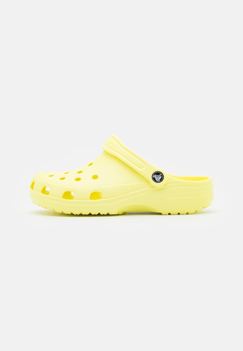 Sabot léger jaune avec des trous de ventilation, une semelle texturée et une bride de talon réglable avec un bouton logo circulaire.
