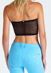 Svart mesh crop-top med ett rektangulärt mönster, som är ihop med ljusblå figurnära jeans med fickdetaljer och en liten logotyp.