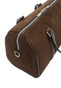 Brązowa zamszowa torba o prostokątnym kształcie, z srebrnym zamkiem błyskawicznym i skórzanymi dodatkami. Posiada zaokrąglone krawędzie oraz dwa krótkie uchwyty.