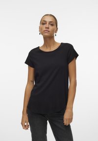 Black short-sleeve t-shirt made of smooth fabric, featuring a round neckline and a slightly curved hem. Worn with dark jeans.