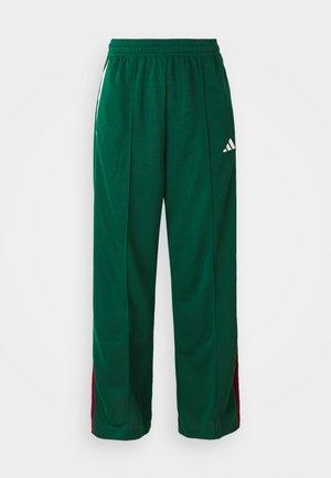 Grønne treningsbukser laget av polyester, med en avslappet passform, elastisk midjebånd, hvite sidestreker og maroon detaljer. Adidas-logo vist.