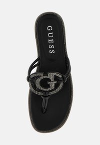 Tongs noires avec une finition brillante, présentant des brides tressées et un logo orné de ton argenté. Semelle intérieure texturée, design épuré.