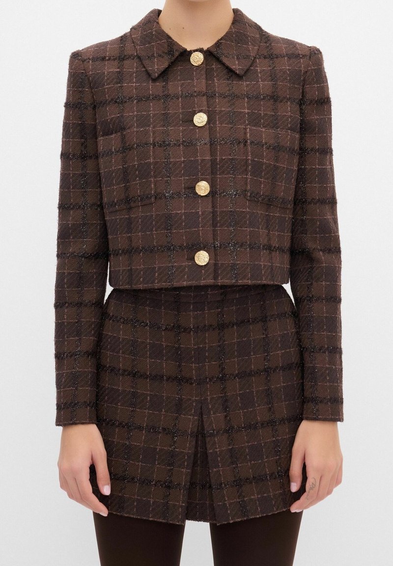 Brun ternet cropped jakke med krave, med guldknapper og en tekstureret finish. Inkluderer to forlommer og lange ærmer.