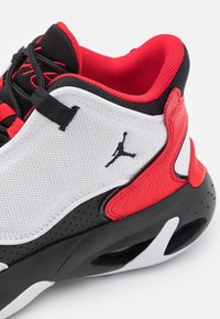 Černé, červené a bílé sportovní boty s síťovaným svrškem, koženými akcenty a perforovanou černou podrážkou. Logo Jumpman je výrazně umístěno na boku.