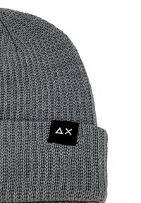 Berretto di maglia grigio con risvolto. Caratterizzato da un'etichetta nera con un logo geometrico bianco. Tessuto morbido con una finitura liscia.