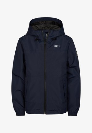 Chaqueta cortaviento azul marino con cremallera frontal, puños elásticos y capucha con cordón ajustable. Se lleva sobre vaqueros azules y zapatillas blancas, con bolsillos laterales.