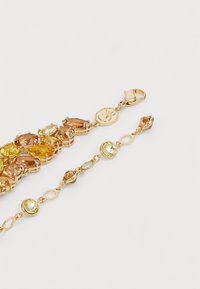 Two gold bracelets with yellow and amber gemstones, featuring lobster clasp closures on a white background.